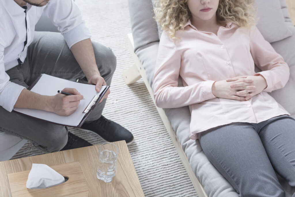 Woman in hypnosis lying on hypnotherapist sofa - hypnotherapy